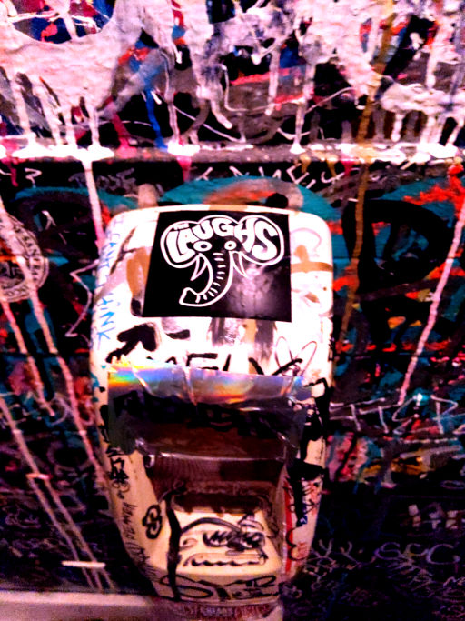 Laughs elephant sticker on a payphone covered in graffiti and stickers