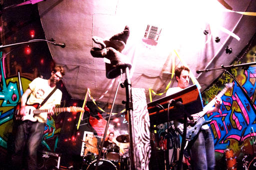 The Laughs performing in a small room with colorful graffiti walls