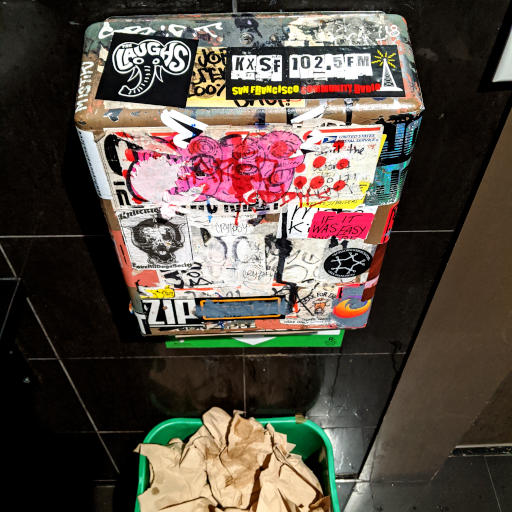 Sticker-covered metal box with a Laughs elephant sticker above a green bin